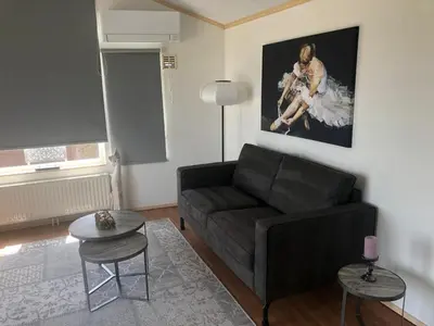 a living room with a black couch and a painting at Chalet nr 17 Park Bergzicht Teuven in Voeren