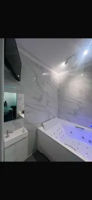 a white bathroom with a tub and a sink at La Suite White wellness Jacuzzi & Sauna in Seraing