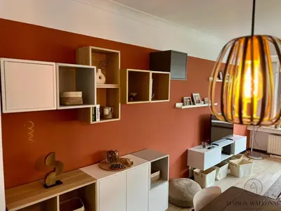a living room with orange walls and white cabinets at L 'écrin sauvenière - Hypercentre avec Parking gratuit in Liège