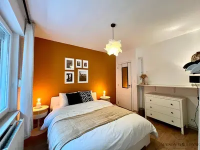 a bedroom with an orange accent wall and a bed at L 'écrin sauvenière - Hypercentre avec Parking gratuit in Liège