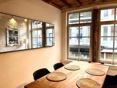 a dining room with a table and some windows at L'Atelier Triplex - Architect's apartment in Liège