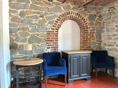 a room with two chairs and a table and a stone wall at La Bushaye in Aubel