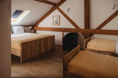 a attic room with two beds and a chair at La Bushaye in Aubel