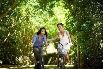 two young women riding bikes down a path at Chalet Bosrust met serre & privéparking Natuur nabij Maastricht in Lanaken
