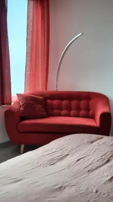 a red couch sitting in a room next to a window at Chambre d'hôte, la rouge in Liège