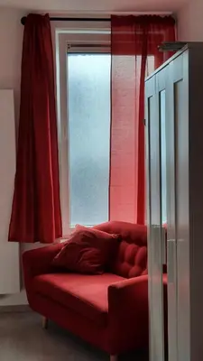 a red couch sitting in front of a window at Chambre d'hôte, la rouge in Liège