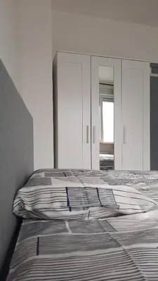 a white bedroom with a bed and a mirror at Chambres d'hôte, la grise in Liège