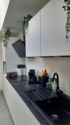 a kitchen with white cabinets and a black sink at Chambres d'hôte, la grise in Liège