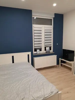 a bedroom with a bed and a blue wall at RELAX Room in Chaudfontaine