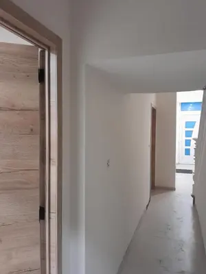 a hallway with white walls and a wooden door at RELAX Room in Chaudfontaine