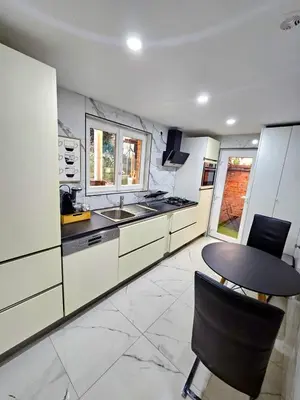 a kitchen with white cabinets and a table and chairs at Jolie petite maison in Liège