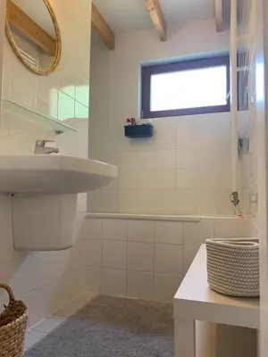 a white bathroom with a sink and a window at Forest lakehouse with Breathtaking Sauna in Lanaken