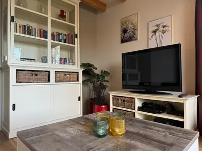 a living room with a tv and a table at Forest lakehouse with Breathtaking Sauna in Lanaken