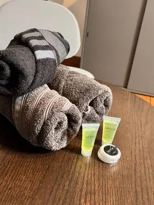 a pile of towels on a table with two cups at Chambre spacieuse privée avec salle de bain privée in Liège