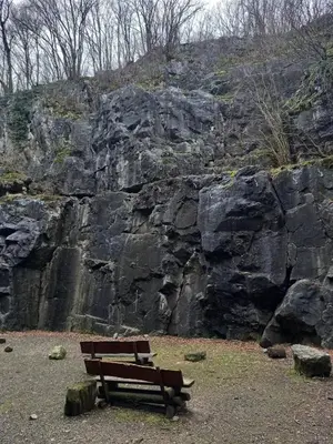 a wooden bench sitting next to a rock wall at Ap57 Nature Ardennes Economy class apartment in Kelmis