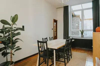 a dining room with a table and chairs and a plant at 2 bedroom apartment near the city center in Liège