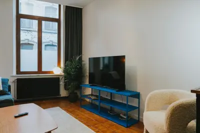 a living room with a flat screen tv on a blue stand at 2 bedroom apartment near the city center in Liège