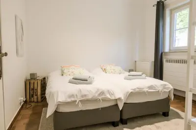 a bedroom with a bed with white sheets and a window at Villa Aluma in Sint-Truiden