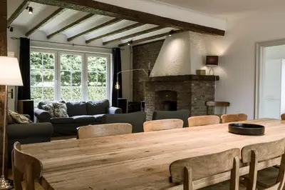 a living room with a wooden table and a fireplace at Villa Aluma in Sint-Truiden