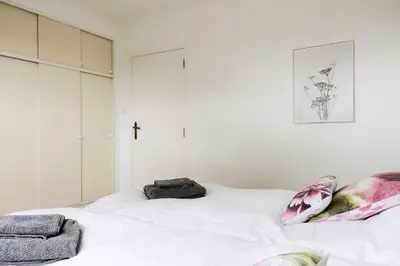 a bedroom with a white bed with a cross on the wall at Villa Aluma in Sint-Truiden