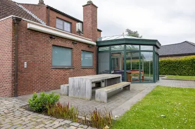 a garden with a bench and a glass house at Villa Aluma in Sint-Truiden