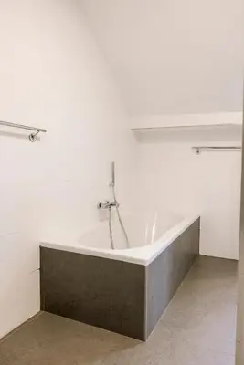 a bath tub in a room with a white wall at Villa Aluma in Sint-Truiden