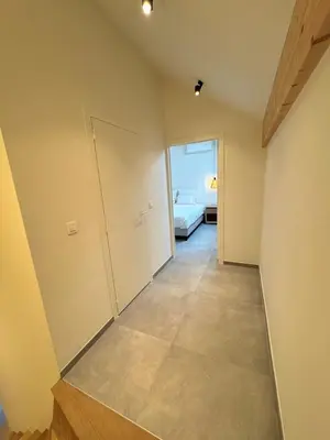 a room with a hallway with a door and a bed at Hartje Borgloon in Borgloon