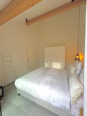 a bedroom with a white bed and a lamp at Hartje Borgloon in Borgloon