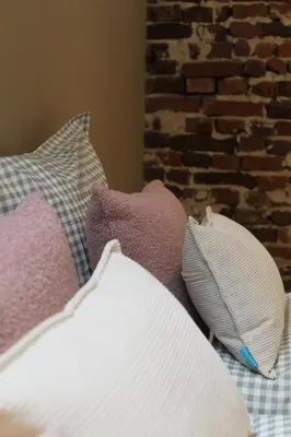 a pile of pillows on a bed with a brick wall at Vakantiewoning Molenveld in Dilsen-Stokkem