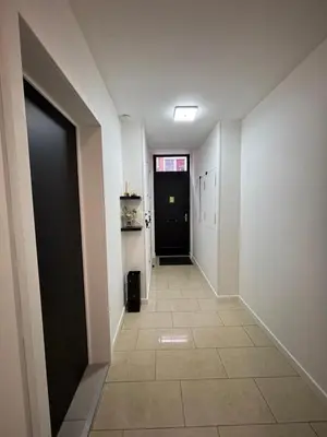 a hallway with a black door and a tile floor at Appartement Hoang in Ans