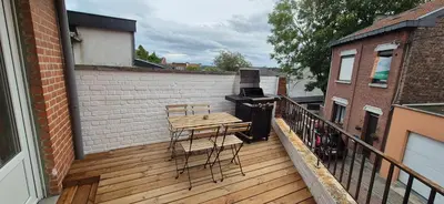 a balcony with a grill and a table and chairs at Appartement Hoang in Ans