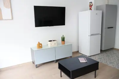 a living room with a white refrigerator and a table at Le Carlton in Liège