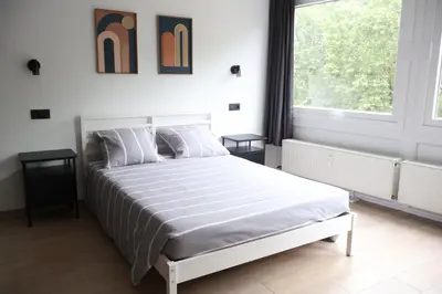 a white bedroom with a large white bed and a window at Le Carlton in Liège