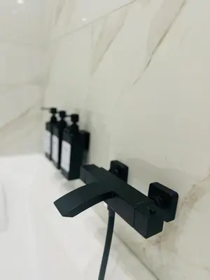 a row of black bottles on a white wall at Élégant appartement avec bain balnéothérapie in Liège