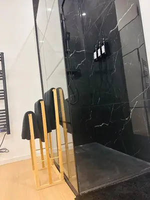 a black marble shower with wooden chairs in front of a mirror at Élégant appartement avec bain balnéothérapie in Liège