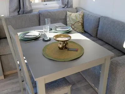 a white table with a plate on it in front of a couch at Camping Zavelbos Superior Chalet in Maaseik