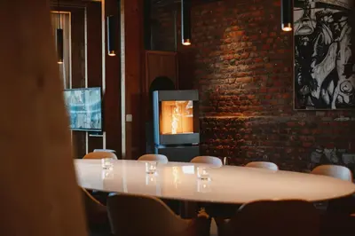 a table and chairs in a room with a fireplace at Art'lette Loft Balneo Bath & Infrared Sauna in Herve