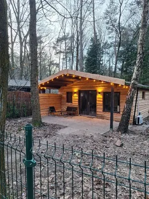 a wooden cabin in the woods with a fence at Sakurahuisje in Lanaken