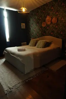 a bedroom with a white bed with a floral wall at ChambreNchill in Seraing