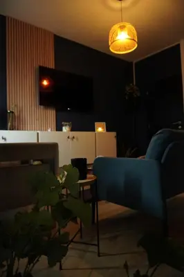 a living room with a blue couch and a lamp at ChambreNchill in Seraing