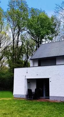 a white building with two chairs in a yard at Vakantiebungalow BERK 1 in Houthalen-Helchteren