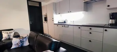 a kitchen with white cabinets and a couch and a counter at Vakantiebungalow BERK 1 in Houthalen-Helchteren