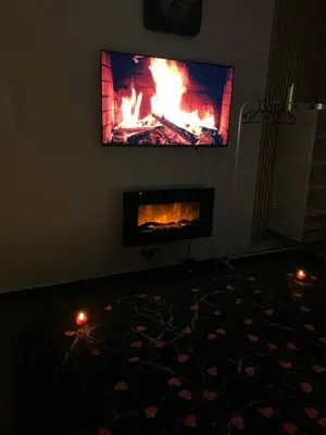 a living room with a fireplace with a flat screen tv at La home Gold Jacuzzi in Seraing