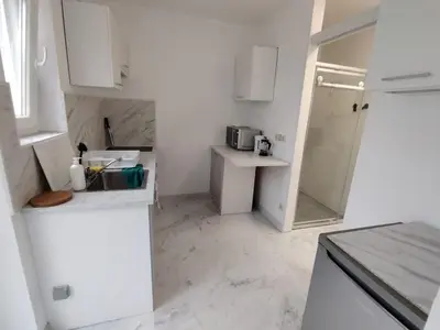 a white kitchen with a sink and a refrigerator at Spacious, warm and cozy studio in Heers