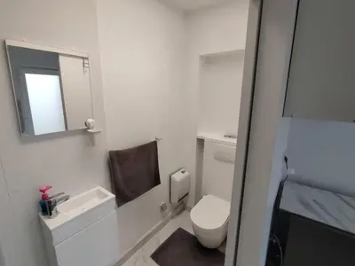 a white bathroom with a toilet and a mirror at Spacious, warm and cozy studio in Heers