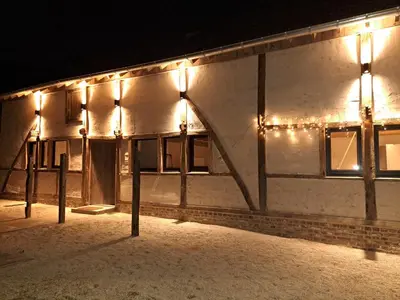 a building with lights on the side of it at night at Hoeve BôThé - Vakantiewoning in Alken