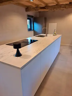 a kitchen with a counter top with a black stool at Hoeve BôThé - Vakantiewoning in Alken