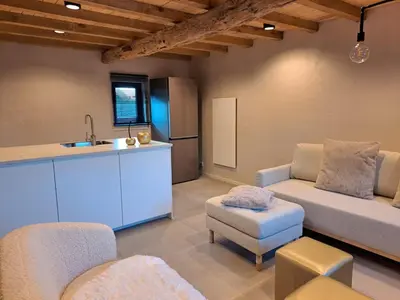 a kitchen with a couch and a chair and a sink at Hoeve BôThé - Vakantiewoning in Alken
