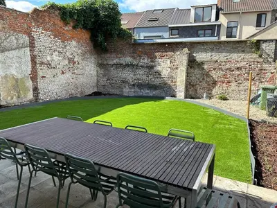 a wooden table and chairs in a yard with a lawn at Vakantiehuis Twenty Six in Hasselt