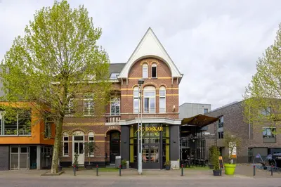 a brick building with a pointed roof on a street at Hotel De Boskar Pelt in Pelt